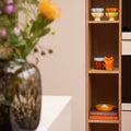 Geschenkbox Cozy Colourful van Collections by Gaav Interieur gestyled in een houten vakkenkast: &klevering Sun schaaltjes, Charlo voorraadpot, oranje Serax Owl vaas en Pudding citruspers