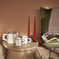 Geschenkbox Slow Living van Collections by Gaav Interieur: Serax Carte Blanche theepot en theekopjes met taper kaarsen op een bijzettafel, naast het TASCHEN boek Great Escapes Italy