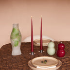 Geschenkbox Table Stories van Collections by Gaav Interieur op een gedekte tafel: Serax Fish & Fish karaf, wijnrode taper kaarsen in zilveren houders en Chubbie peper- en zoutmolens