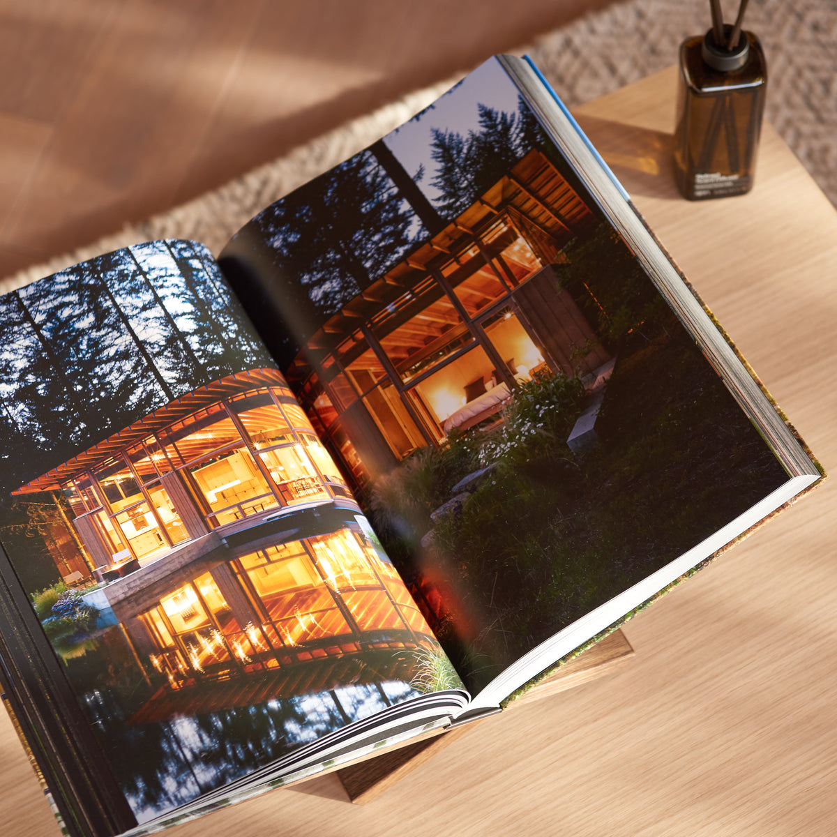 Geschenkbox Welcome Home van Collections by Gaav Interieur: TASCHEN Homes for Our Time opengeslagen op de handgemaakte eikenhouten boekenstandaard, met Ajen Wilderloof geurstokjes