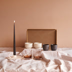 Inhoud geschenkbox Morning Ritual: Serax Dune kopjes in Alabaster en Slate, Zuma glazen in Amber, Mira kandelaar met espresso taper kaars en LIND DNA teak dienblad