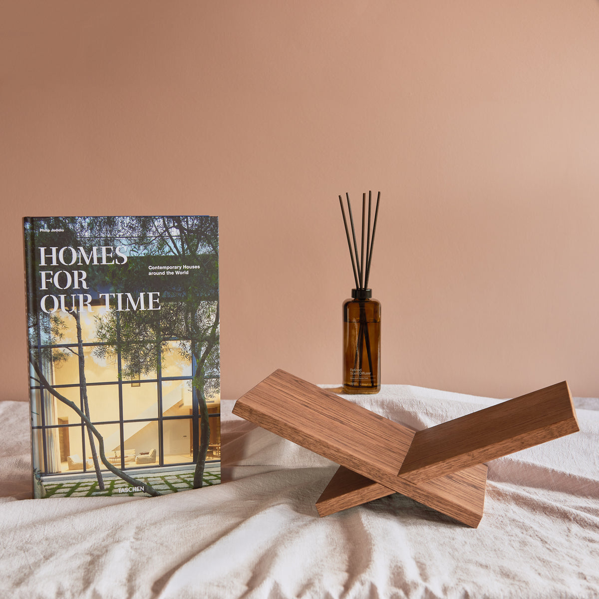 Inhoud van geschenkbox Welcome Home: TASCHEN boek Homes for Our Time, handgemaakte eikenhouten boekenstandaard van Gaav Interieur en Ajen Wilderloof geurstokjes